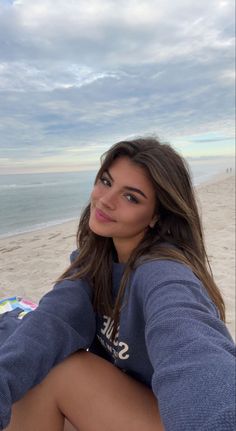 a woman sitting on the beach with her legs crossed