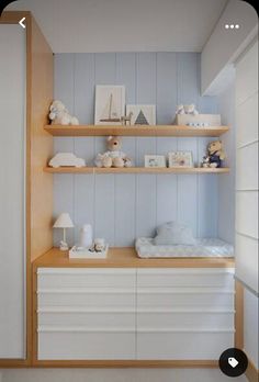 a baby's room with blue walls and shelving unit in the corner,