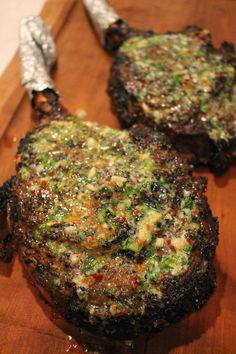 two grilled steaks sitting on top of a wooden cutting board