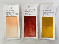 three different shades of red, yellow, and orange on white paper with tags attached to them