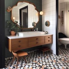 a bathroom with a sink, mirror and stool in the corner next to it is tiled flooring