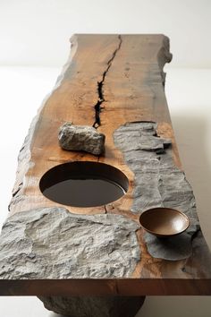 a piece of wood with two bowls on it and some rocks in the middle, sitting on a white surface