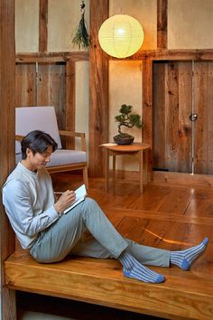 a person sitting on a wooden floor reading a book