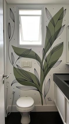 a white toilet sitting under a bathroom window next to a sink and shower head mounted on a wall