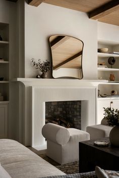 a living room filled with furniture and a fire place under a mirror on the wall