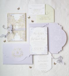 the wedding stationery is laid out on top of each other, with butterflies flying around