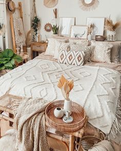 a bed with pillows and blankets on top of it next to a wicker table