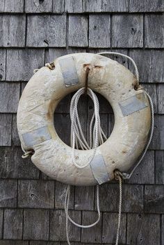 an old life preserver hanging on the side of a wooden building next to a brick wall