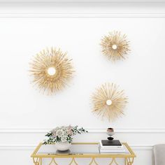 a living room with three sunburst wall decorations on the walls and a gold console table