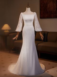 a mannequin dressed in a white wedding dress with long sleeves and lace detailing