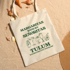 a tote bag sitting on top of a beach next to shells and starfish