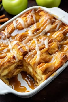 a casserole dish with apples and cinnamon drizzled around it on a table