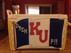 a cooler with the letter k u painted on it's side sitting on a wooden floor