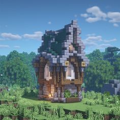 a small house made out of blocks in the middle of a green field with trees and bushes