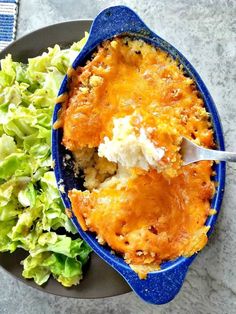 a blue dish filled with food next to a salad