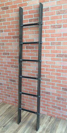 a ladder leaning against a brick wall in front of a wood flooring area with wooden floors