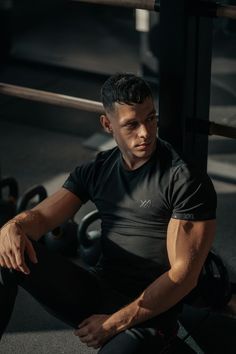 a man sitting on the ground in front of a barbell