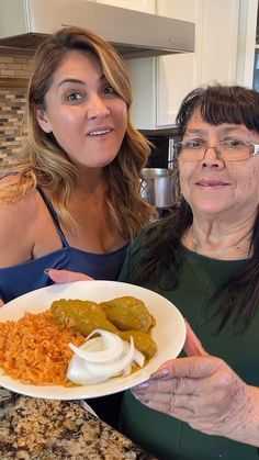 two women are posing for the camera while holding a plate of food in front of them