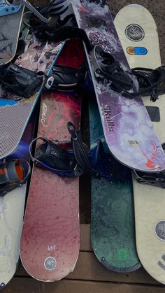 a pile of snowboards sitting on top of a wooden floor next to each other