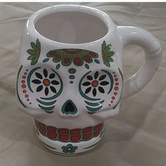 a white ceramic sugar skull mug sitting on a bed