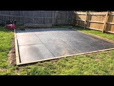 a backyard area with a concrete slab in the middle and grass around it, surrounded by a fence