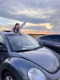 a woman is waving from the top of a car