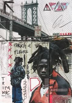 a man with dreadlocks standing in front of a graffiti covered fence and bridge