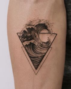 a black and white photo of an ocean wave with a triangle tattoo on the arm