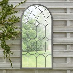 an arched glass window sitting on top of a wall next to a green plant in front of it