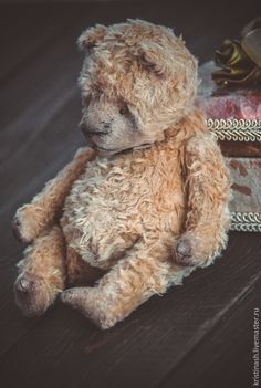 a brown teddy bear sitting on top of a wooden table