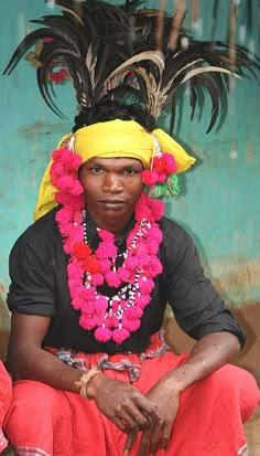 a woman sitting in front of a blue wall with feathers on it's head