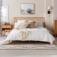 a bed with white sheets and pillows in a room next to a dresser, mirror and lamp