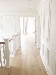 an empty hallway with white walls and wood floors