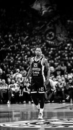 a man standing on top of a basketball court in front of a crowd at a game