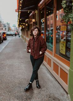 a woman standing on the sidewalk in front of a store