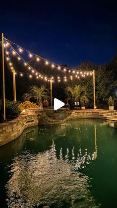 an outdoor swimming pool with lights strung over it