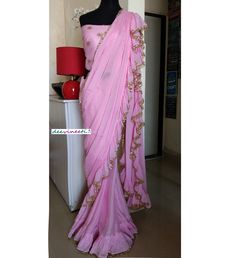 Color : Pink Fabric - Chinon This Ruffled Saree has beautiful Crystal Scallop trim at the hemline. Length of Saree 48 inches. Blouse : Pink Emroidered Net with Silk Lining The blouse and underskirt/petticoat will be stitched as per the measurements provided IF YOU WISH TO PURCHASE THIS WE CAN SEND A VIDEO ON YOUR WHATSAPP NUMBER FOR BETTER UNDERSTANDING OF THE SAREE Fabric Care : Dry Clean Only Disclaimer: The actual color of the product might slightly differ from the image due to photographic l Fitted Georgette Sharara With Embroidered Border, Elegant Pre-draped Saree With Embroidered Border For Wedding, Pink Georgette Pre-draped Saree With Embroidered Border, Fitted Sharara With Embroidered Border For Party, Fitted Floor-length Lehenga With Embroidered Border, Wedding Sharara With Embroidered Border In Georgette, Fitted Georgette Lehenga With Embroidered Border, Fitted Pre-draped Saree With Embroidered Border For Party, Silk Saree With Ruffles For Wedding