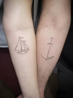 two people with matching tattoos on their arms holding each other's hands, one has a sailboat and the other has a boat