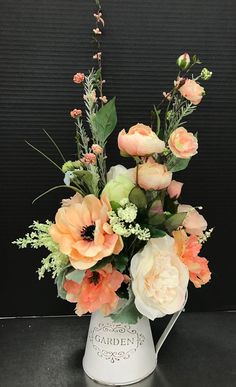 a white pitcher filled with lots of flowers on top of a black table next to a wall