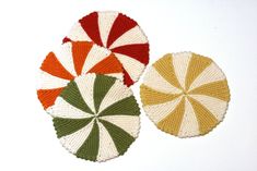 three crocheted coasters with different colors and designs on them, one in the shape of a lollipop