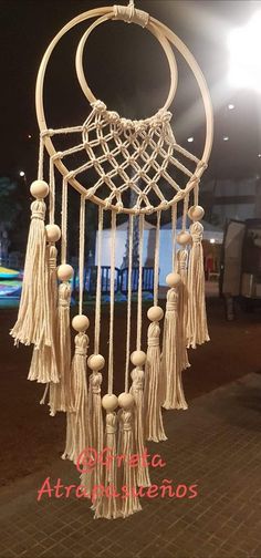 a white dream catcher with tassels hanging from it's sides on a brick sidewalk