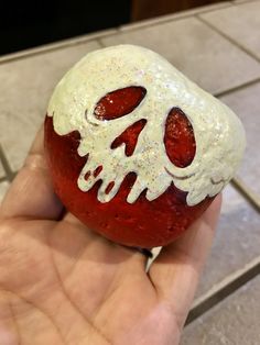 a hand holding a strawberry with white icing and a skull on it's side