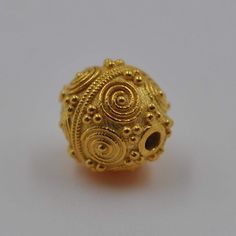 a gold bead is shown on a white surface