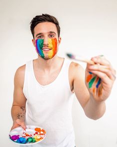 a man with paint on his face holding a plate and brush