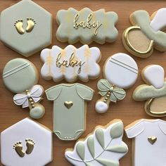 baby shower cookies are arranged on a wooden table with gold trimmings and decorations