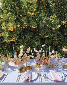 the table is set with oranges and flowers