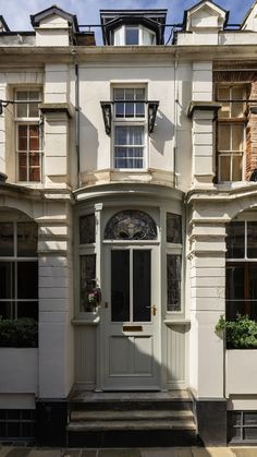 a white building with many windows and plants on the front door is pictured in this image