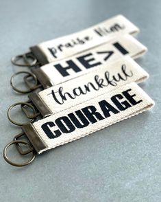 three keychains with words on them that say thank, thanks, and courage