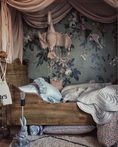 a bed with pillows and blankets on top of it in front of a floral wallpaper