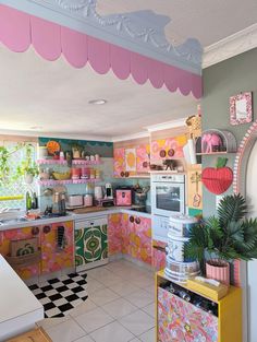 a kitchen with pink and yellow decor on the walls